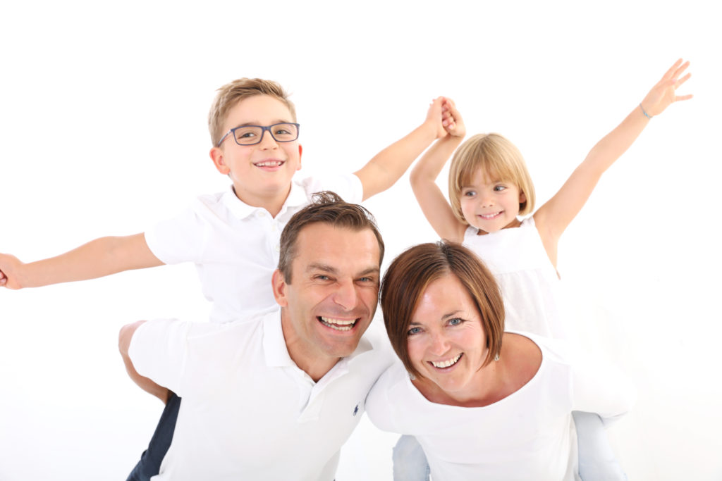 Moderne Familienaufnahme mit farblich abgestimmten Outfits, auf weißem Hintergrund. Fotoshooting mit der Familie in Wien: Die schönsten Ideen