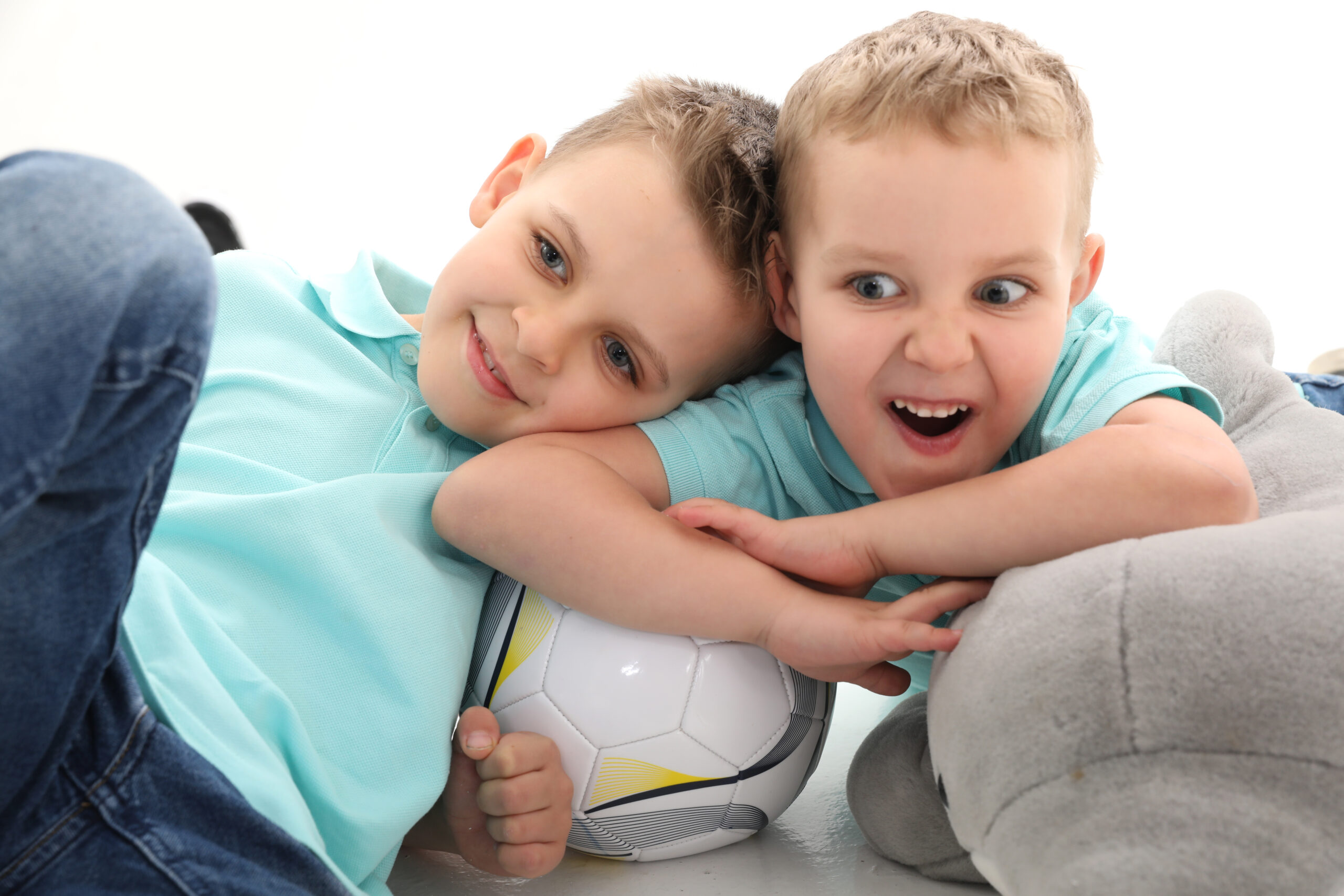 Zwei glückliche Jungen mit einem Fußball liegend
