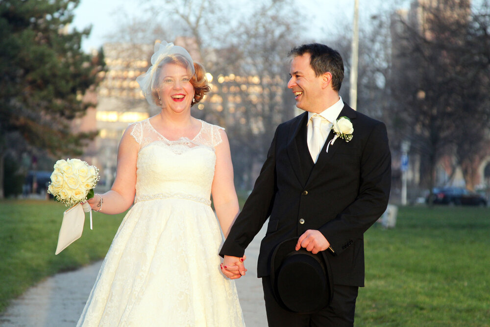 Lächelndes Brautpaar spaziert Hand in Hand im Park, im warmen Licht der Sonne