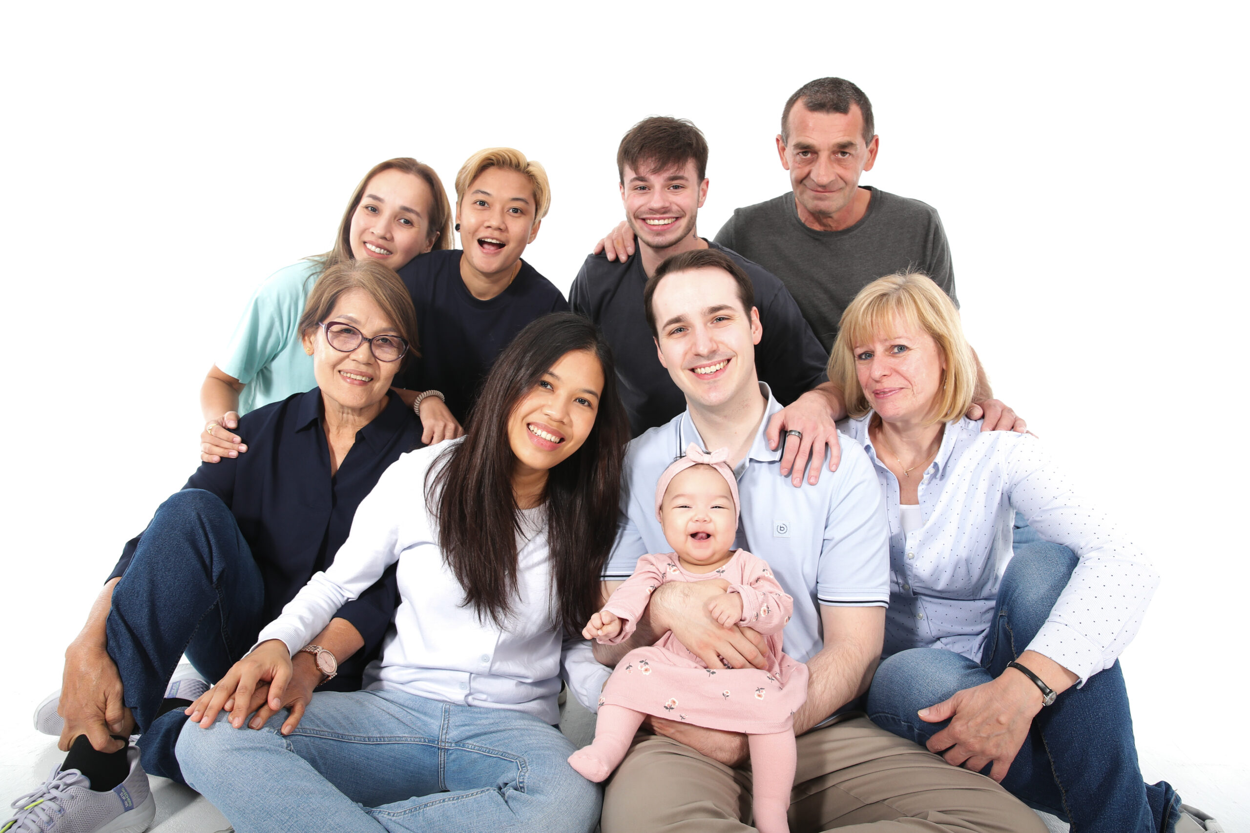 Glückliche, vielfältige Familie mit acht Personen und einem lächelnden Baby, das im Mittelpunkt steht