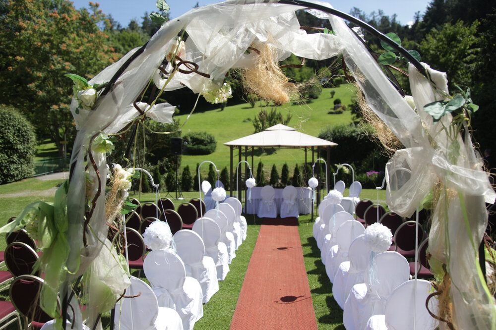 Freiluft-Hochzeitszeremonie mit geschmücktem Bogen und Stuhlreihen auf einer Wiese