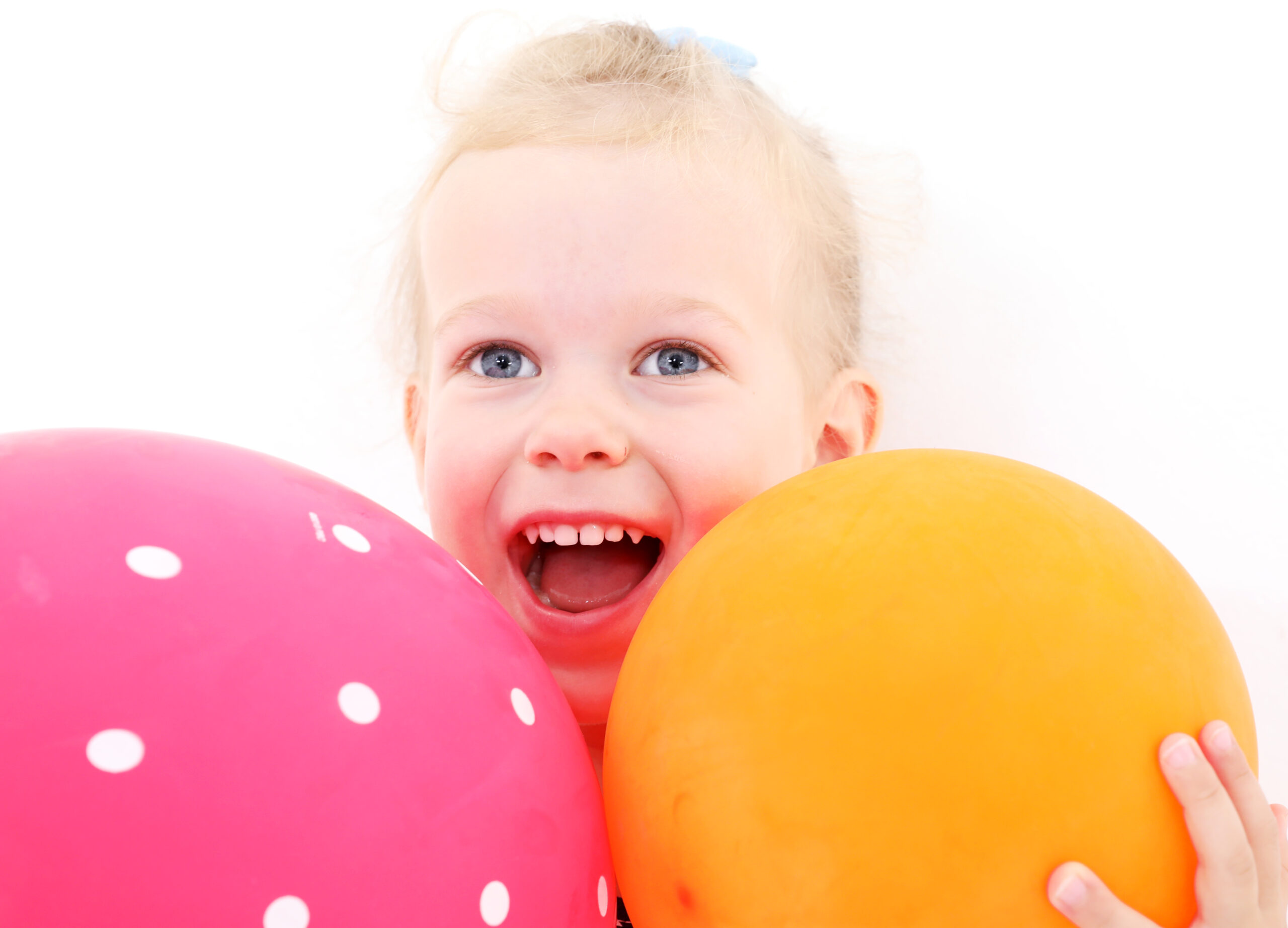 Kleines lächelndes Mädchen hält zwei bunte Luftballons