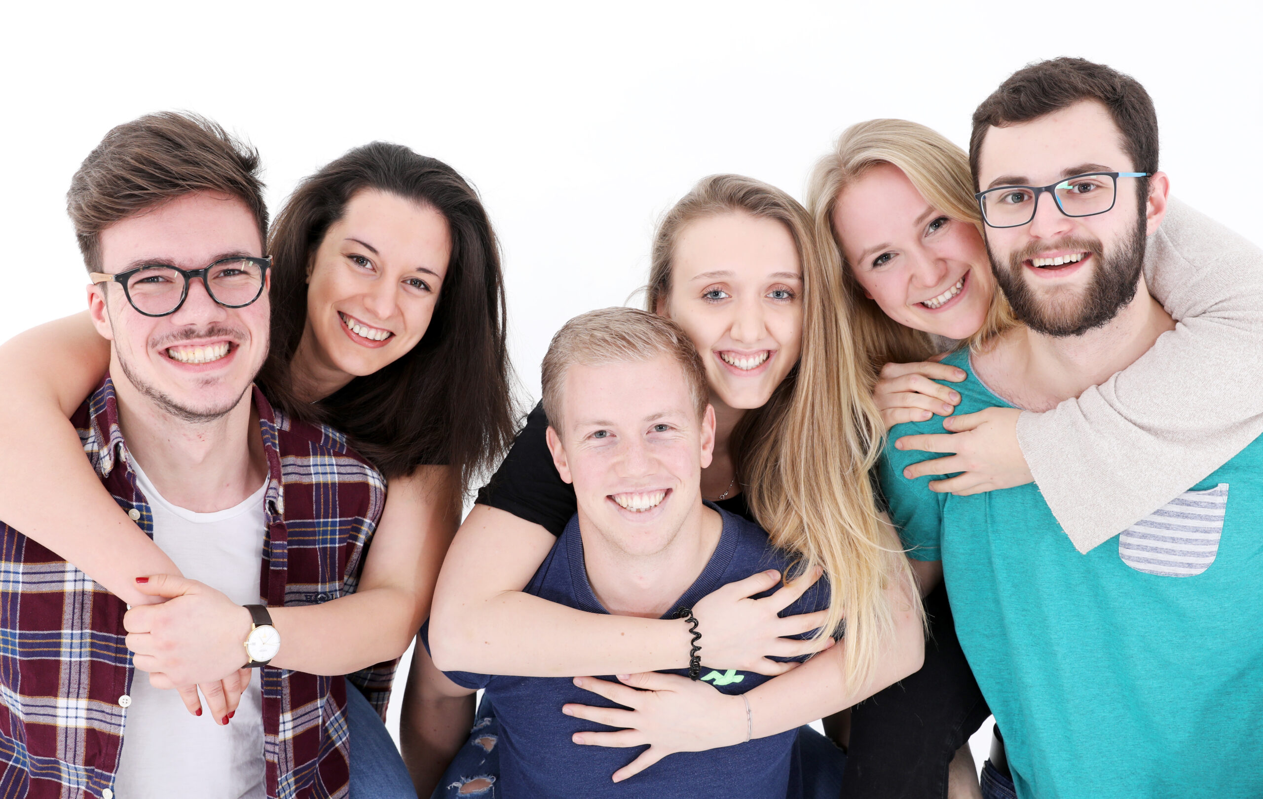 Fünf lächelnde junge Erwachsene umarmen sich in freundschaftlicher Pose vor einem weißen Hintergrund