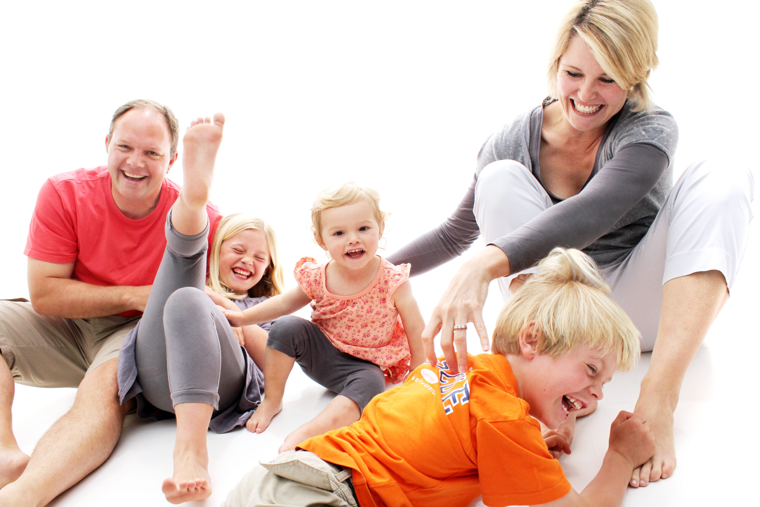 Eine glückliche Familie spielt und lacht zusammen auf einem weißen Hintergrund.